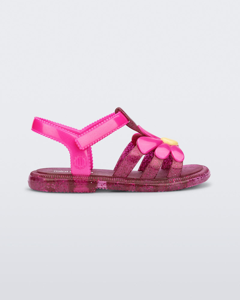 Side view of a glitter pink baby Hip Bloomy sandal with pink straps and flower