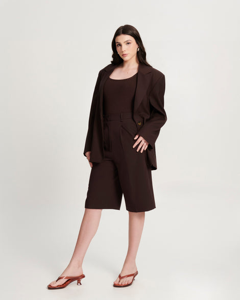 Model in a black short suite set wearing a pair of brown Flip Flop Kitten Heels with clear brown straps