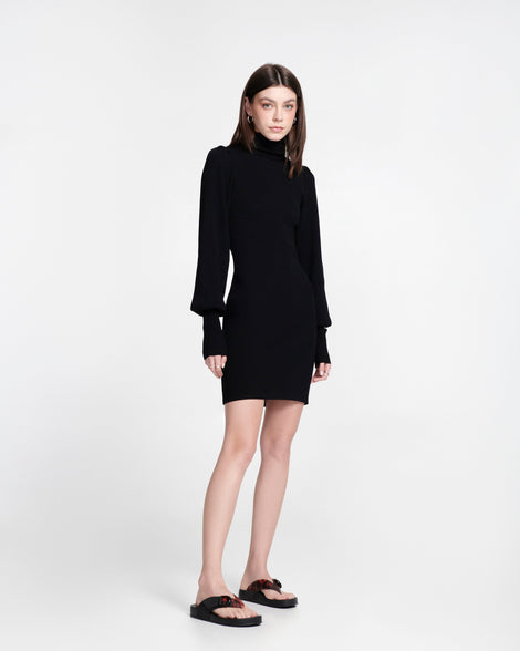 Model in s black dress wearing a pair of black Cozy Thong Flip flops with brown tortoise strap