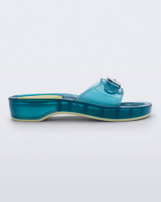 Side view of a clear blue Pescura Heel + Scholl slide with top buckle