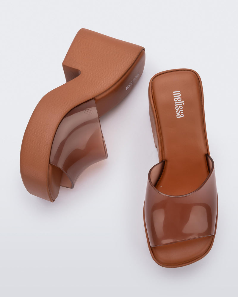 Top and side  view of a pair of transparent brown Posh platform mule