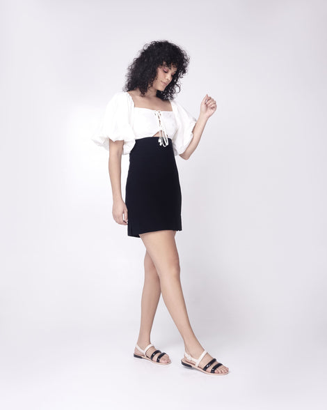 Model in a black and white dress wearing a pair of black and beige Essential Wave women's sandal with adjustable buckle.