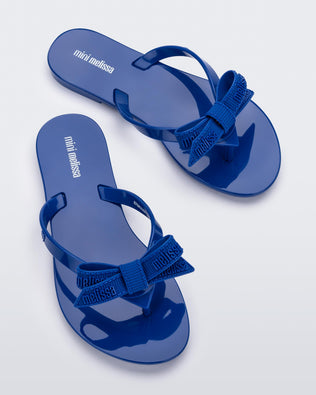 Top view of a pair blue Harmonic M Lover kids flip flops with Melissa logo on bow