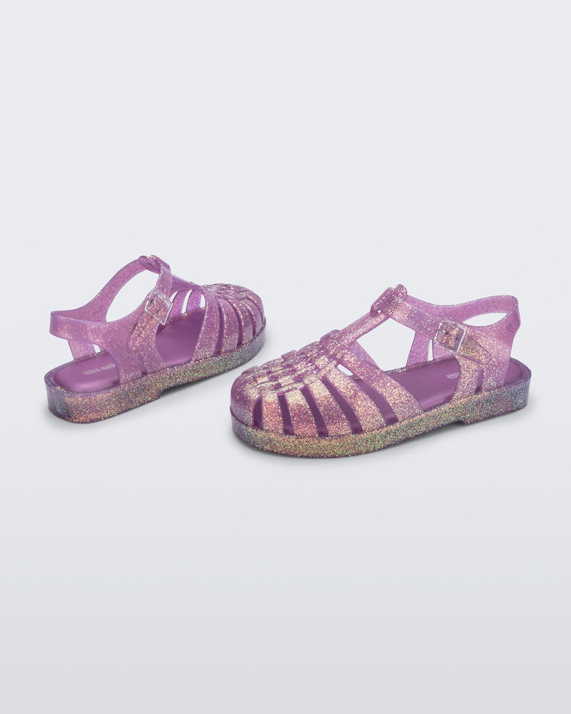Top and angled view of a pair of glitter lilac kids Possession sandals