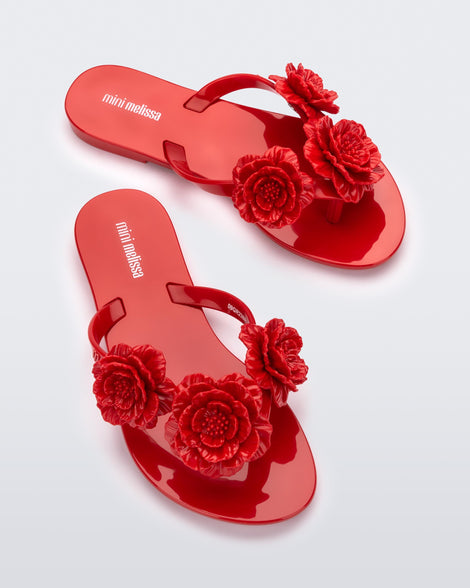 Top view of a pair of a red Harmonic Springtime kids flip flop with three red flowers.