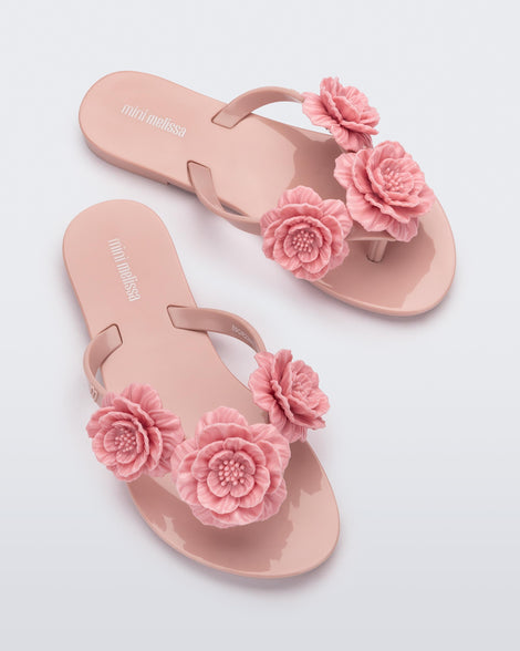 Top view of a pair of a pink Harmonic Springtime kids flip flop with three pink flowers.