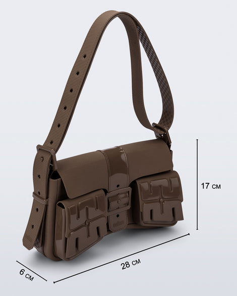 Angled view of a brown Cargo bag with two small pockets on the front and an adjustable strap with measurements of the bag: 28cm x 6cm x 17cm