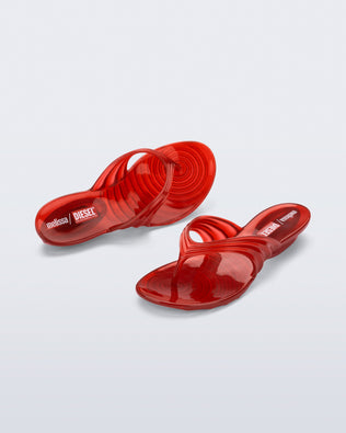 Top and angled view of a pair of transparent red Flip Flop + Diesel sandals