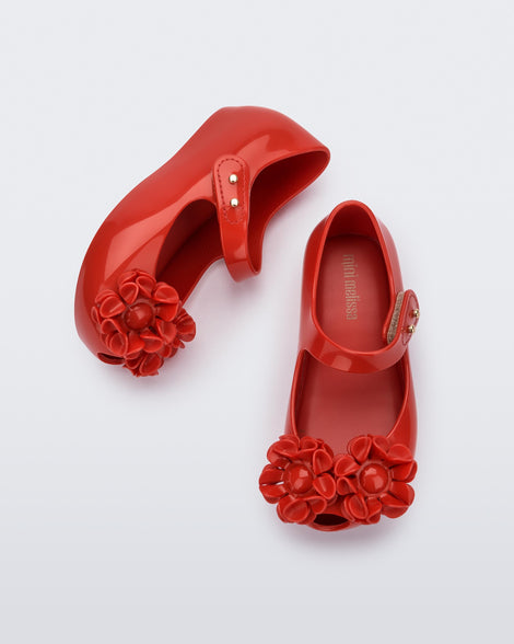 Side and top view of a pair of a red Ultragirl Springtime baby flat with two red flowers and peep toe.