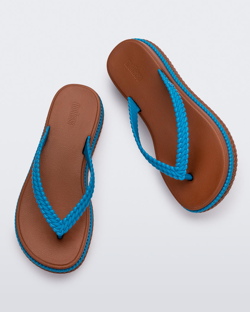 Top view of a pair of brown/blue Melissa Leblon platform flip flops with details that mimic sisal braids on the sole and strap