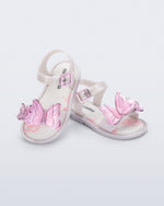 Angled view of a pair of pearly white baby Butterfly sandals with pink butterflies