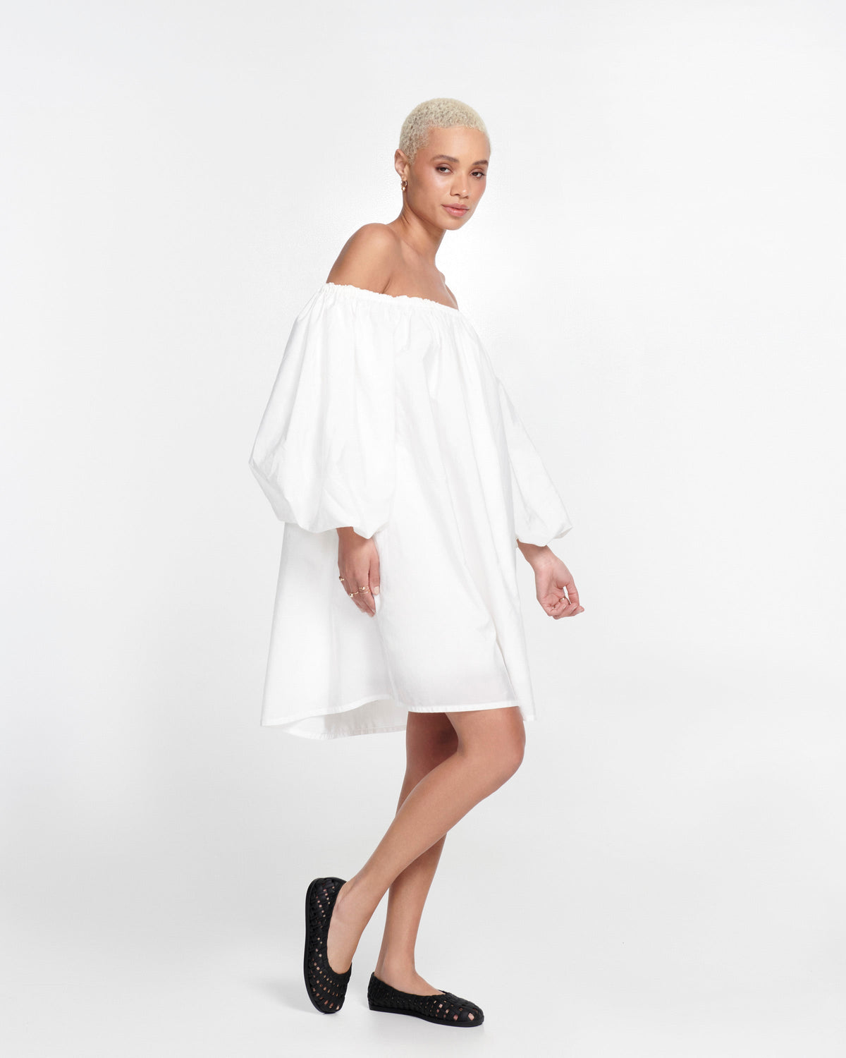 Model in a white dress wearing a pair of black Possession Ballerina flats