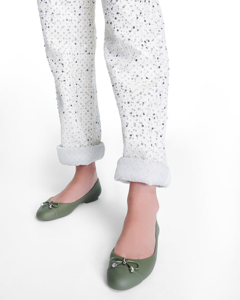 Models legs wearing a pair of green Melissa flats with a bow detail with gold accents on the bow