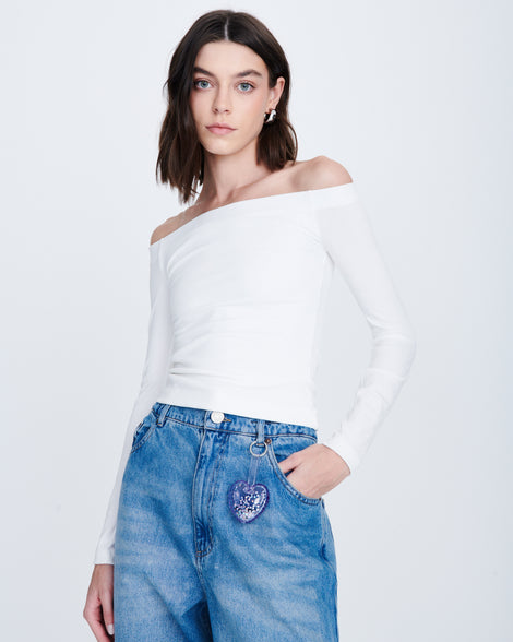 Model in a white shirt and jeans with a clear with glitter Heart bag charm attached to her belt buckle
