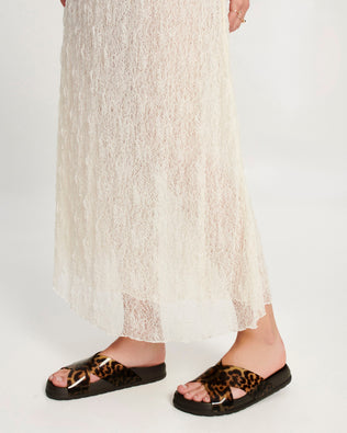 Model's legs in a pair of dark brown/tortoise Cozy Cross sandals with crisscross top straps