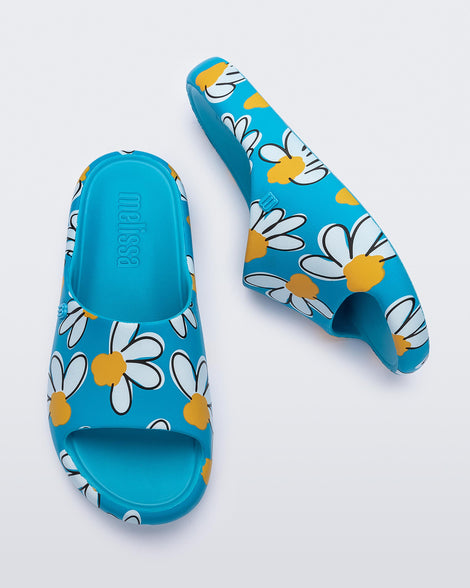 Top and side view of a pair of blue Free Print Slides with daisy print flowers