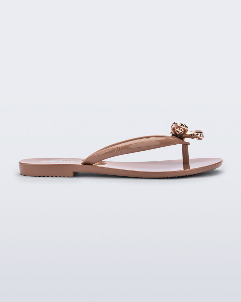 Side view of a brown Harmonic Iris flip flop with rose gold bow