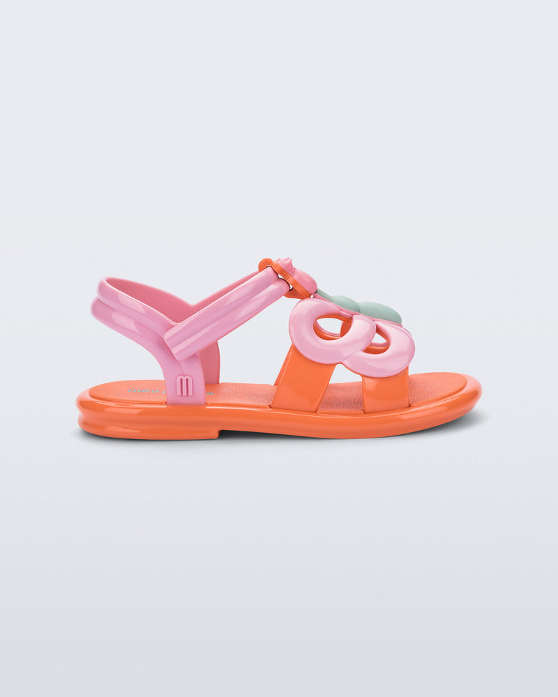 Side view of a pink strap, orange sole Hip Butterfly baby sandal