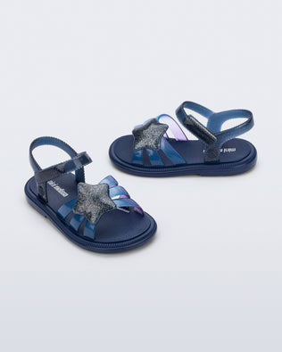 Side and angled view of a pair of glitter blue Hip Sky baby sandals with a glitter blue star on top