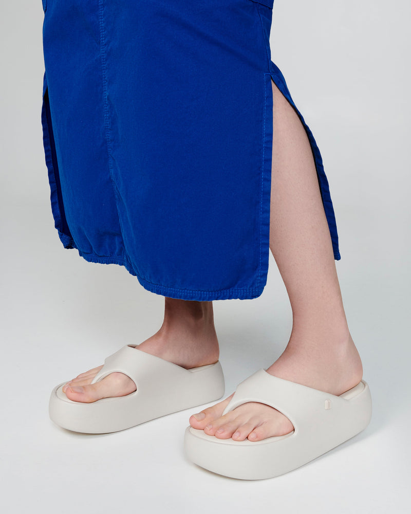 Model's legs in a blue skirt wearing a pair of beige Free Platform Thongs