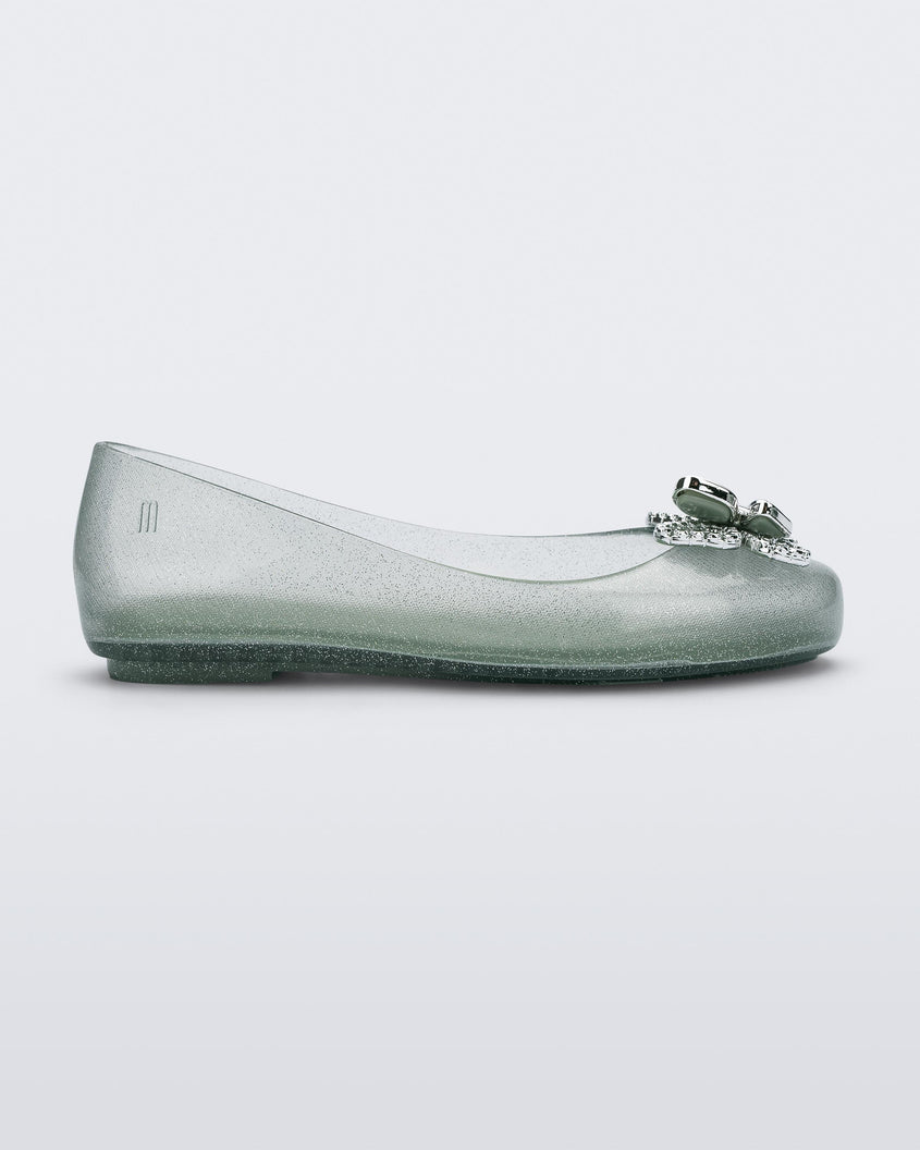 Side view of a glitter green Mini Melissa Sweet Love Butterfly flat with a silver butterfly detail on the toe