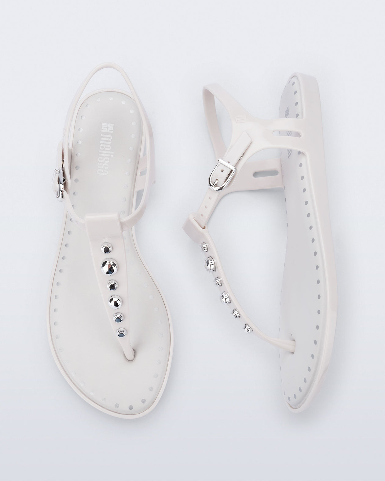 Top and Side view of a pair of white Solar Boho t-strap sandals with ,metallic detailing on the front strap