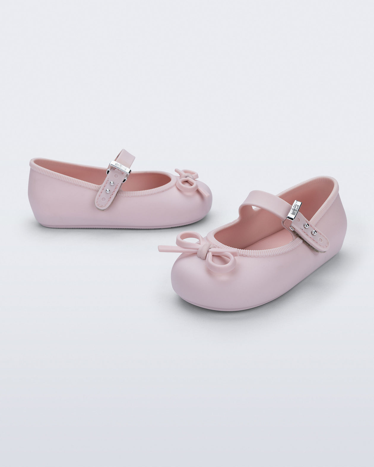 Side and angled view of a pair of pink Soft Ballerina Delicate Bow baby flats with top strap and bow