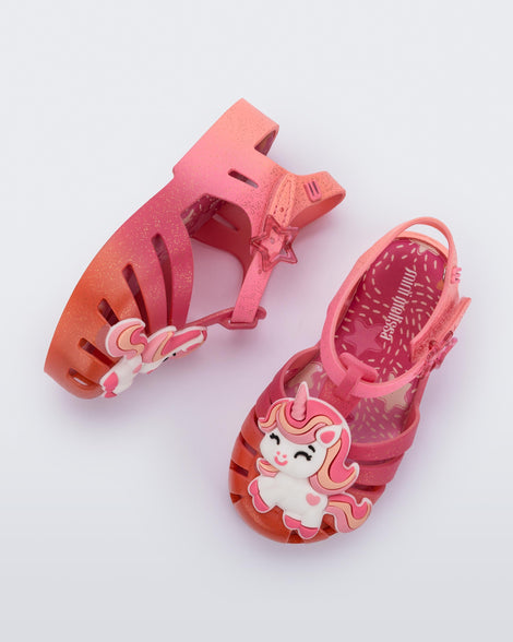 Side and top view of a pair of pink/orange Possession Unicorn baby sandals with unicorn on front upper