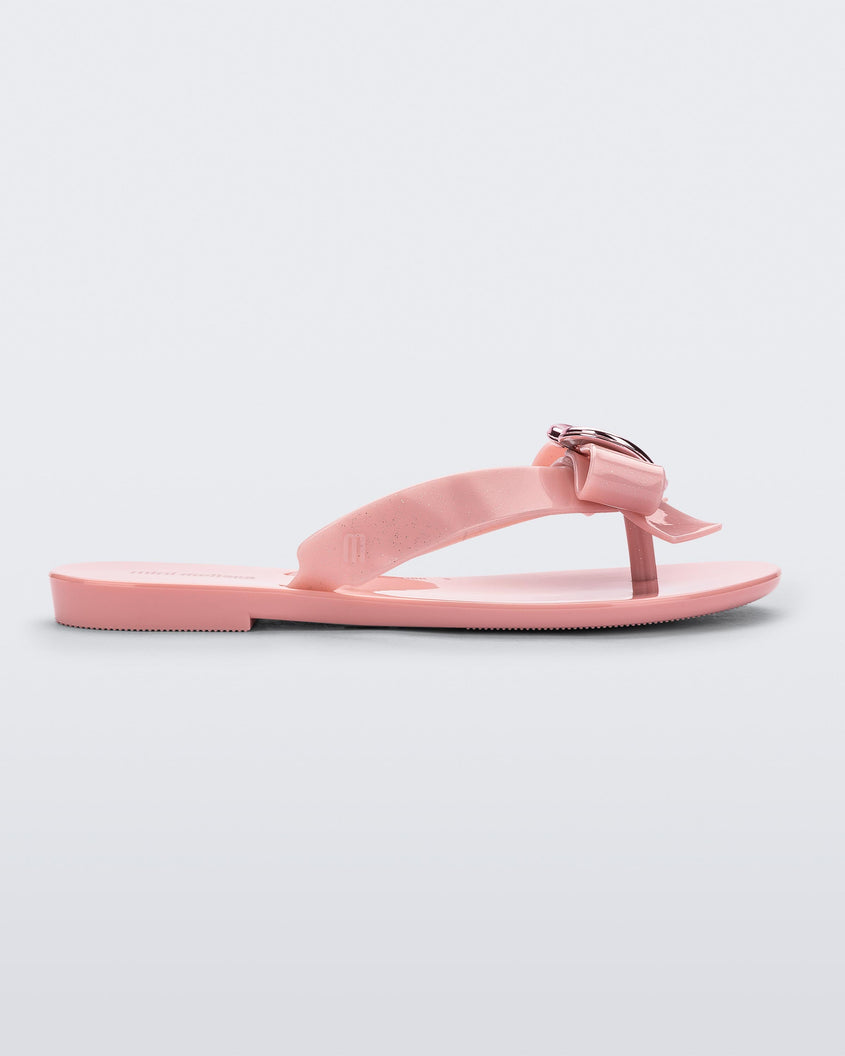 Side view of a pink Mini Melissa Harmonic Heart flip flop with a pink bow and metallic pink heart detail on the straps