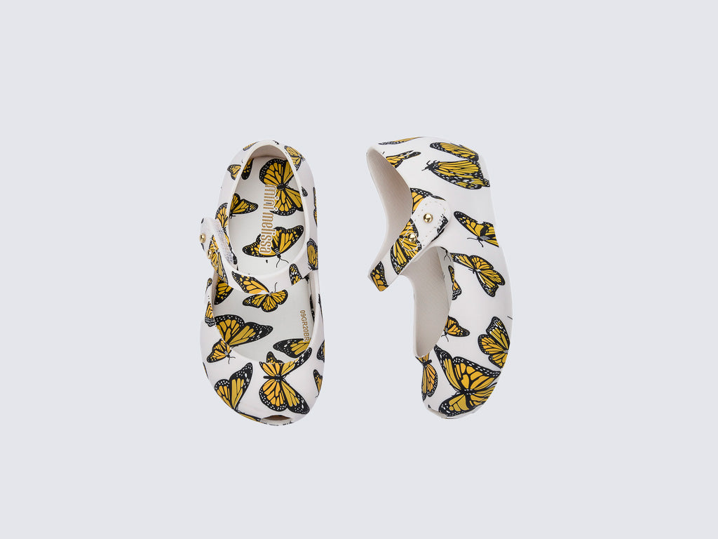 Top and side view of a pair of white Ultragirl Print baby ballerinas with orange and black butterflies