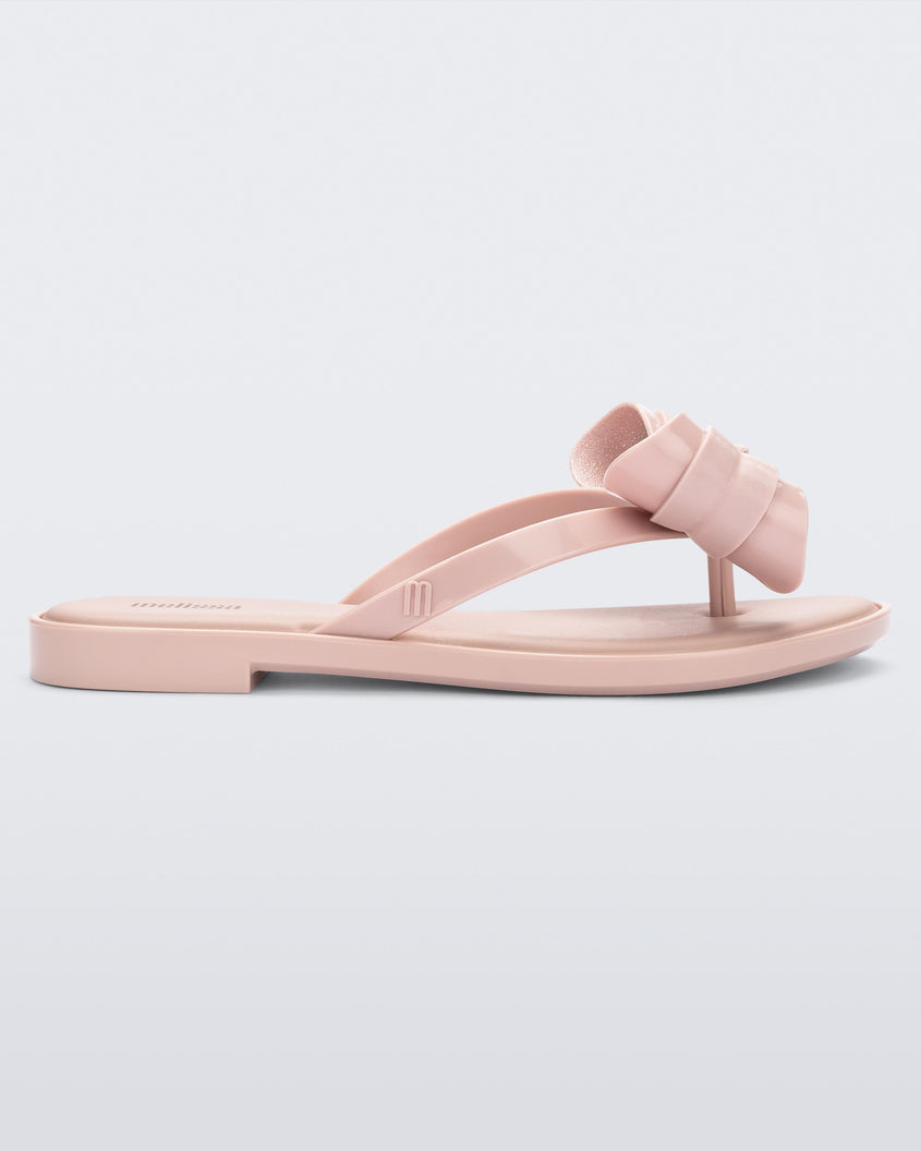 Side view of a Melissa slim strap flip flop in glitter pink with bow applique