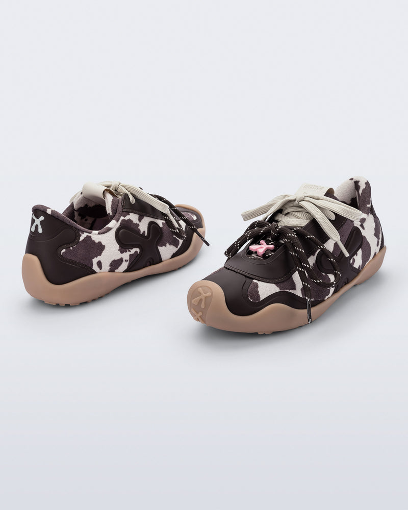 Back and angled view of a pair of black and white cow print X Bend sneakers with beige sole