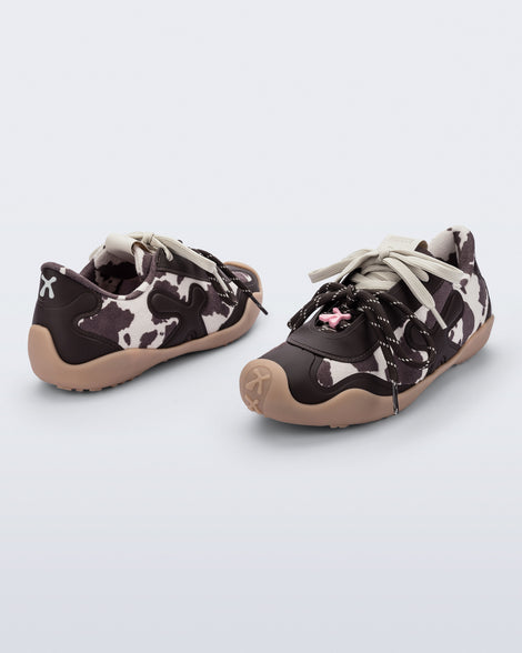 Back and angled view of a pair of black and white cow print X Bend sneakers with beige sole