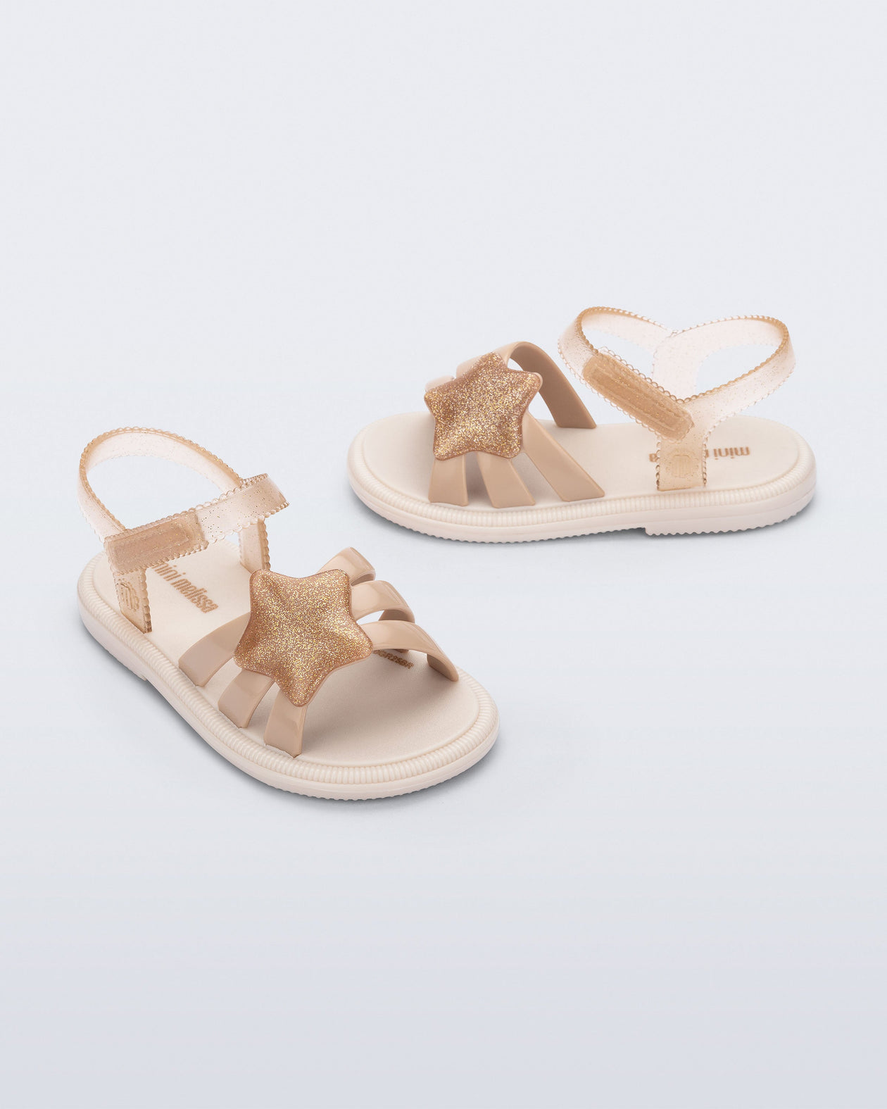 Side and angled view of a pair of beige Hip Sky baby sandals with a glitter beige star on top