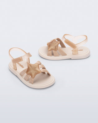 Side and angled view of a pair of beige Hip Sky baby sandals with a glitter beige star on top