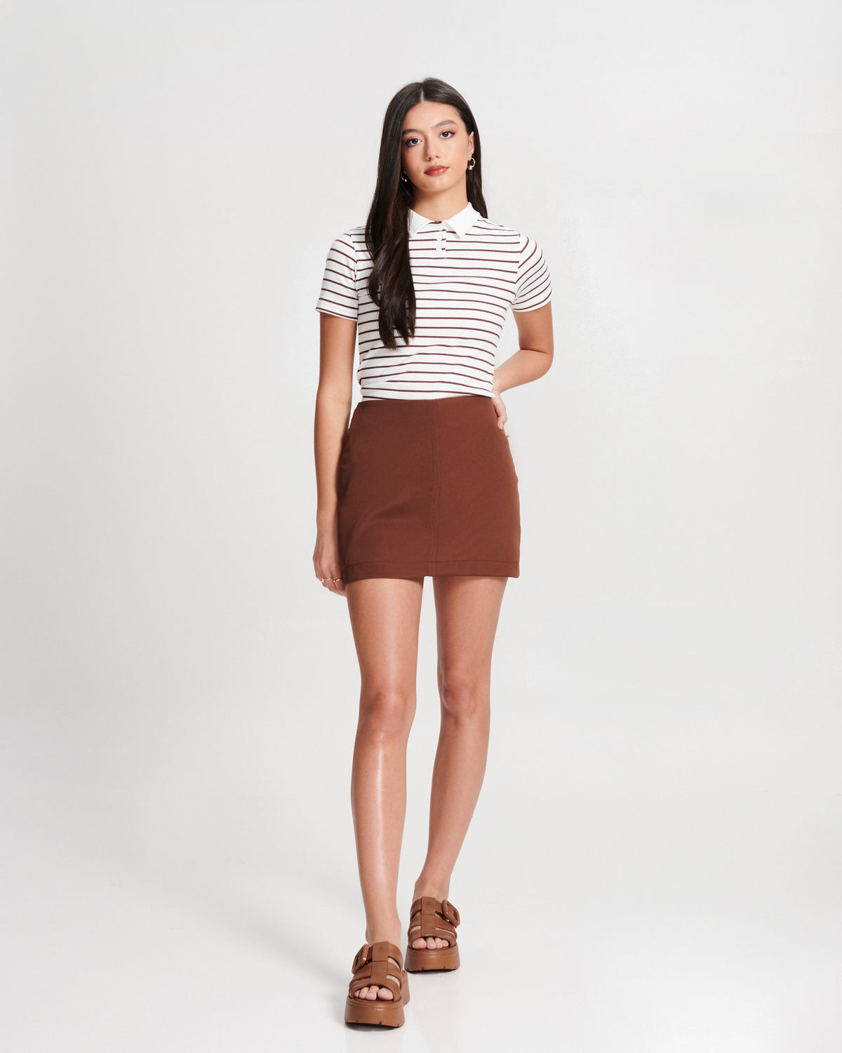 Model in a white stripped shirt and brown skirt wearing a pair of brown  Pump Platform sandals