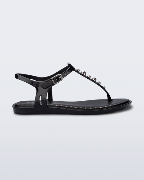 Side view of a black Solar Boho t-strap sandal with ,metallic detailing on the front strap