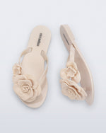 Top and side view of a pair of beige Harmonic Petals kids flip flops with flowers