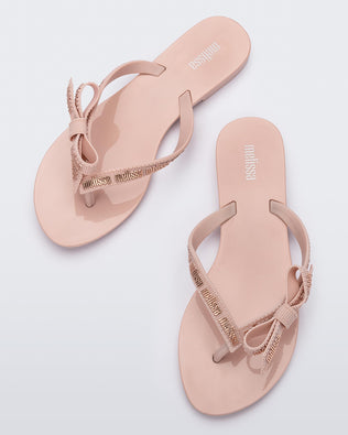Top view of a pair of light pink Harmonic M Lover adult flip flop with Melissa logo on strap