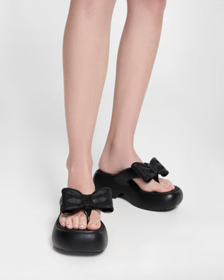 Model's legs wearing a pair of black Free Fuzzy Platform flip flops