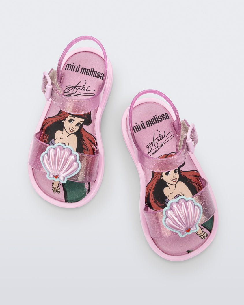 Top view of a pair of glitter pink Mini Melissa Mar Sandal Princess sandals with a seashell detail on the front strap, an ankle strap and Princess Ariel soul
