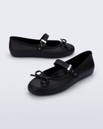Side and angled view of a pair of black Soft Ballerina Delicate Bow flats with top strap and bow