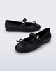 Side and angled view of a pair of black Soft Ballerina Delicate Bow flats with top strap and bow