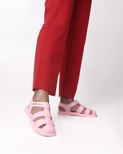 Model's legs in red  pants wearing a pair of pink Emma women's sandals.