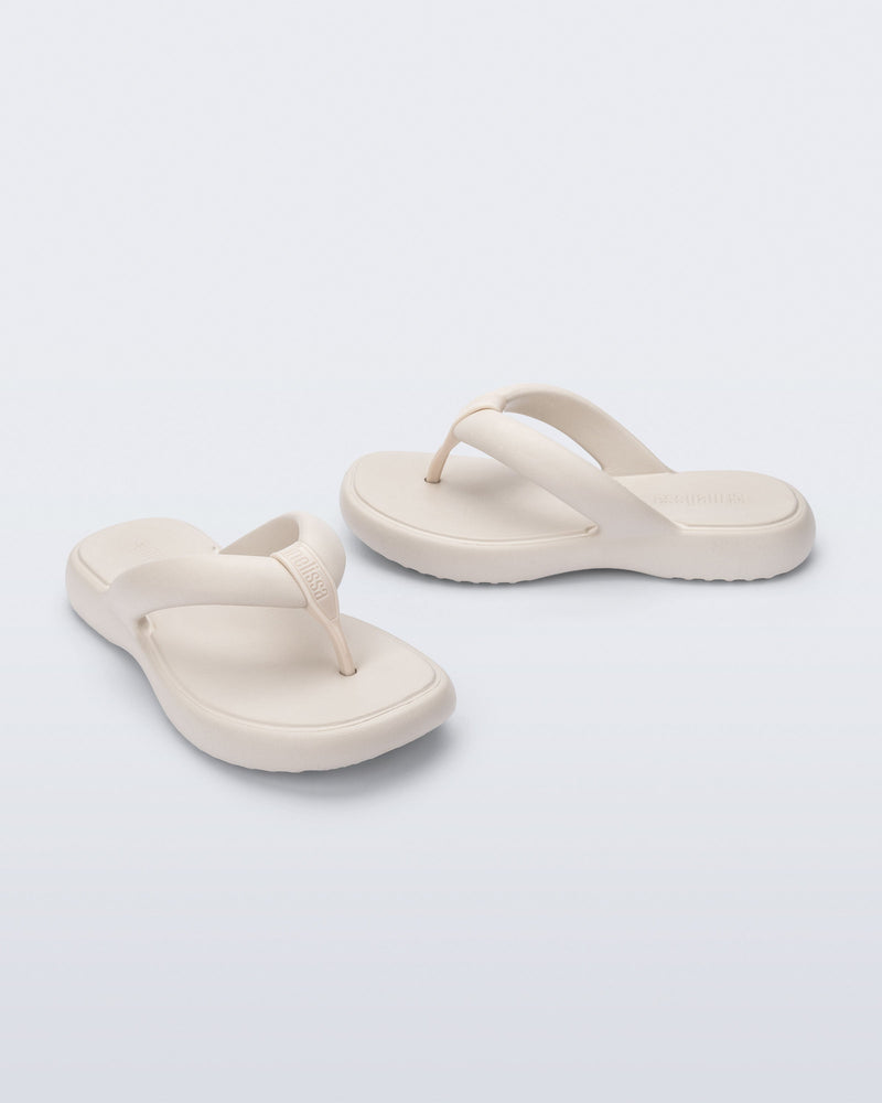 Side and angled view of a pair of beige Free Low flip flops