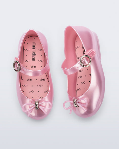 Top and angled view of a pair of pearly pink Sweet Love baby flats with bow