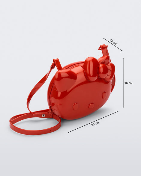 Angled view of a red Hello Kitty + Friends Cute Bag with the face of Hello Kitty with measurements 21cm x 10cm x 16cm