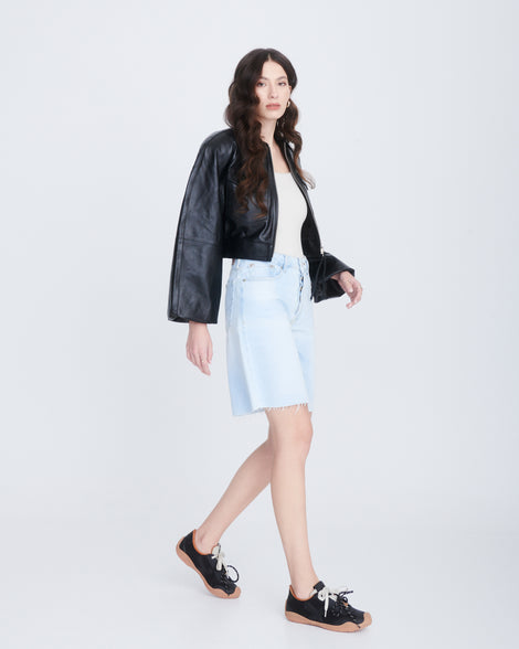 Model in jean shorts and black jacket wearing a pair of black X Bend sneakers with beige sole