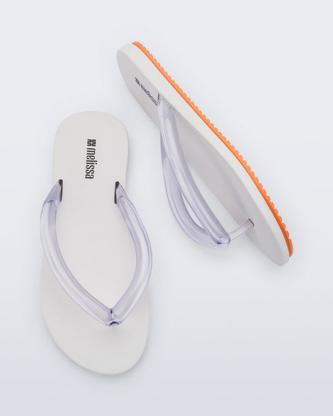 Top and side view a pair of white Flip Flop Airflow sandal with a clear strap and orange bottom