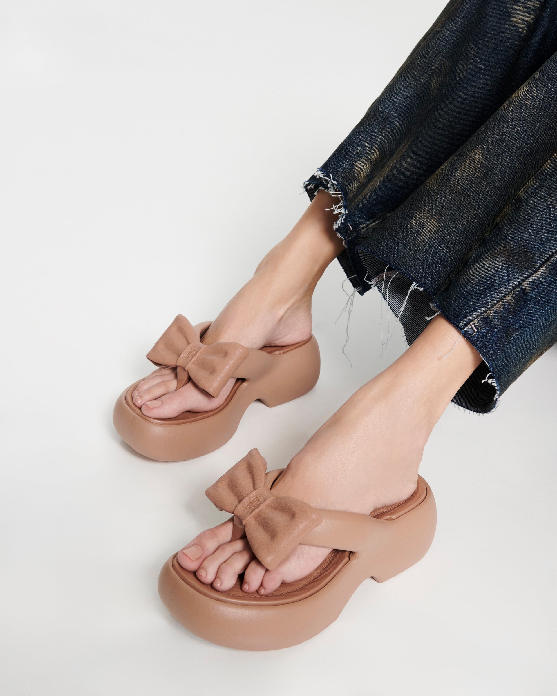 Model's legs wearing a pair of brown Free Fuzzy Platform flip flops
